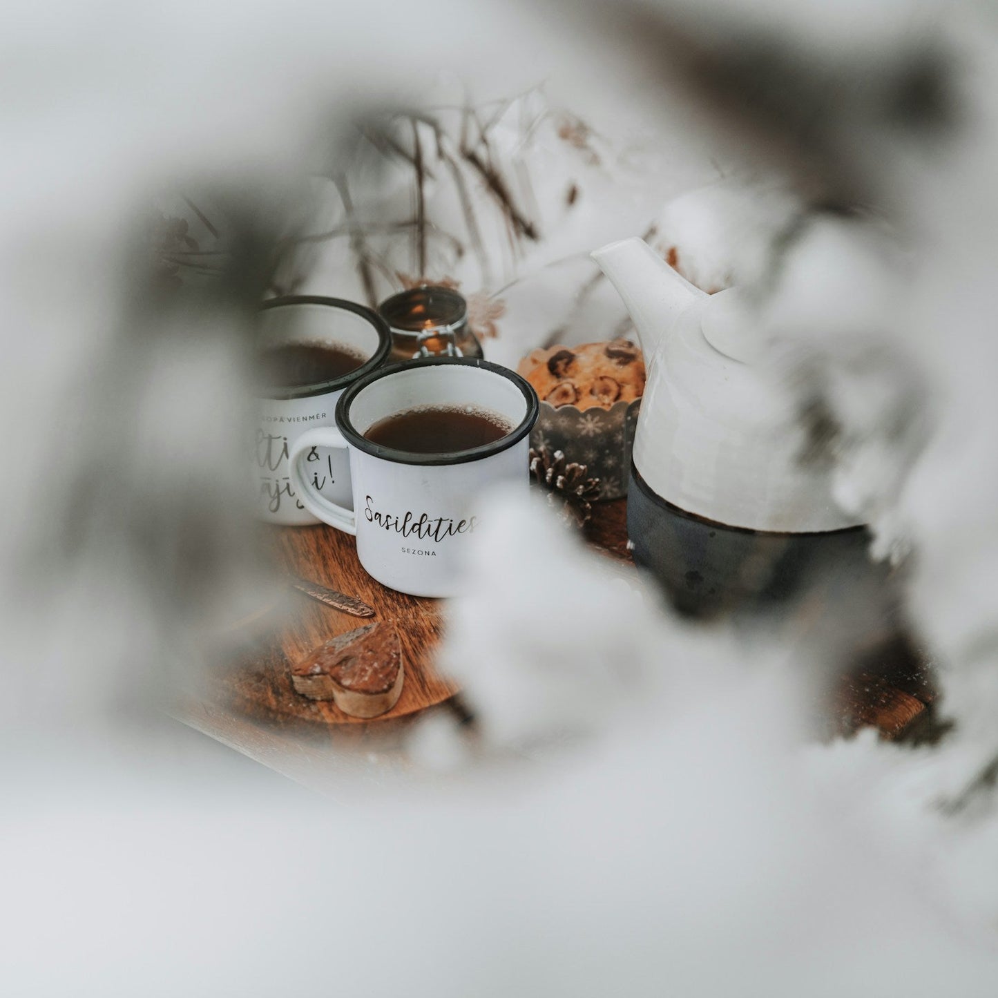 winter scene with two cups of black tea viewed between snow-covered tea branches. | Cove Tea Co.
